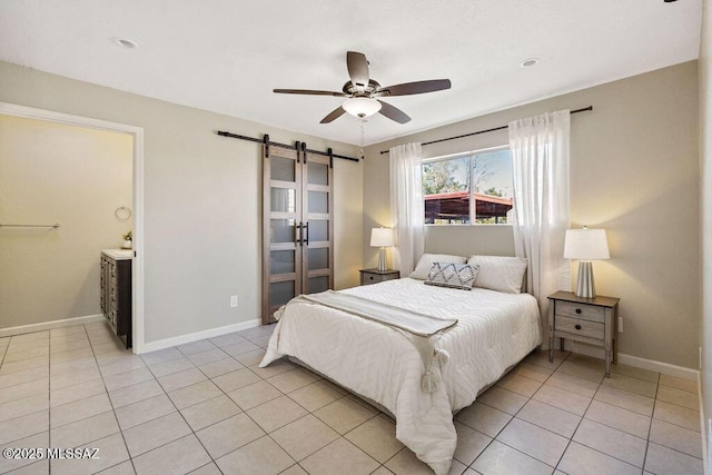 tiled bedroom with a barn door, ceiling fan, and ensuite bathroom