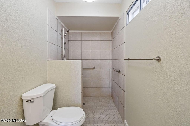 bathroom featuring a tile shower and toilet