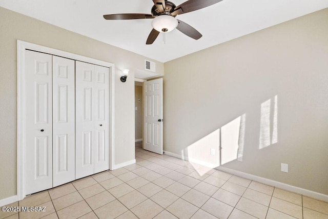 unfurnished bedroom with light tile patterned floors, ceiling fan, and a closet