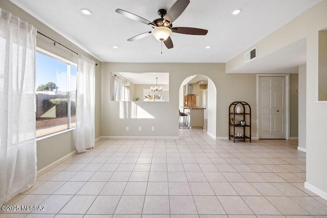 spare room with ceiling fan with notable chandelier and light tile patterned flooring