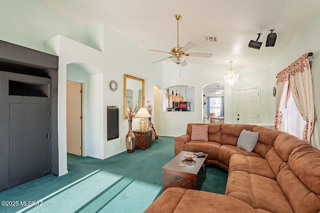 living room featuring ceiling fan, carpet floors, and a towering ceiling