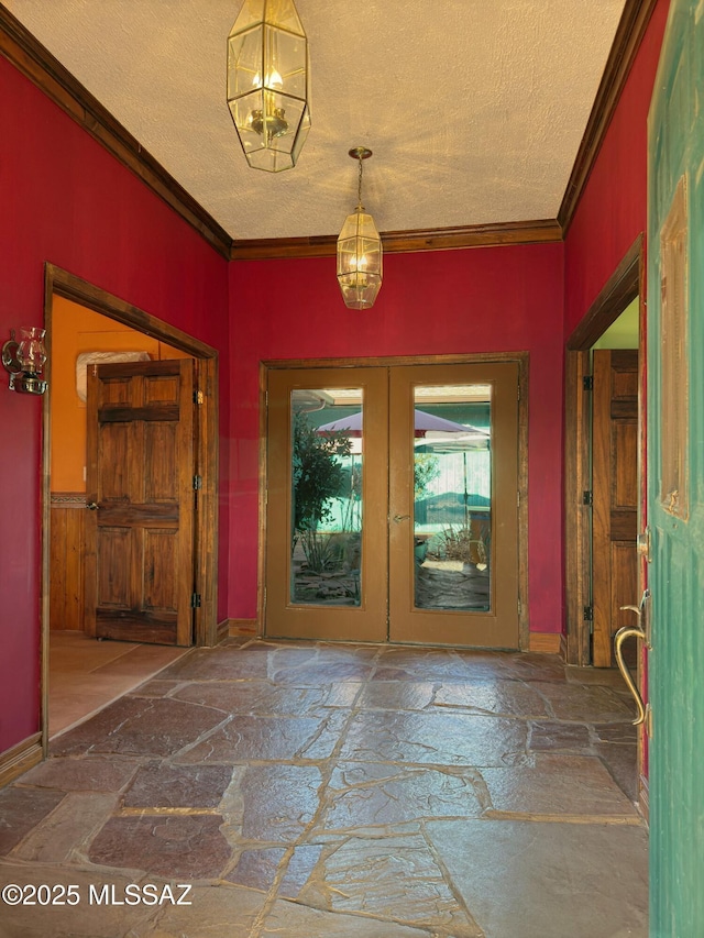 entrance foyer featuring ornamental molding, a textured ceiling, and french doors