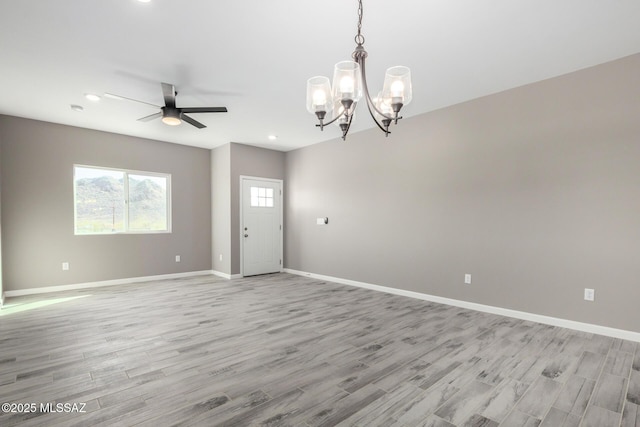 empty room featuring ceiling fan with notable chandelier and light hardwood / wood-style flooring