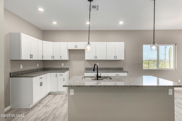 kitchen featuring stone countertops, sink, hanging light fixtures, and white cabinets