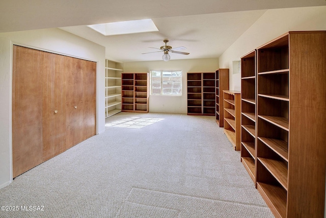 interior space with a closet, light carpet, ceiling fan, and a skylight