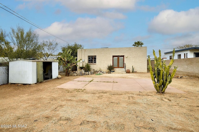 rear view of house with a shed and a patio area