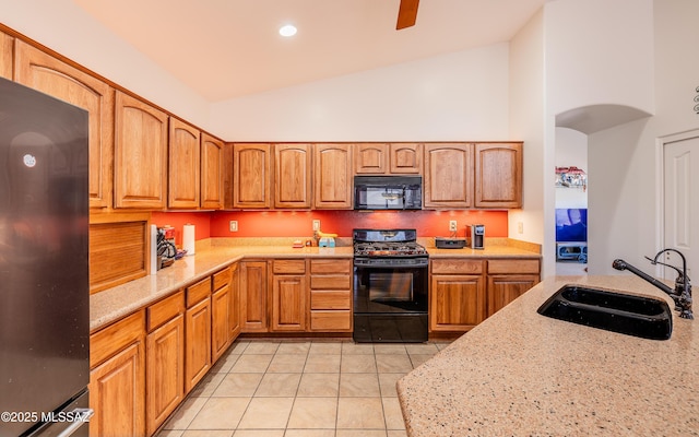 kitchen with light stone counters, light tile patterned flooring, sink, and black appliances