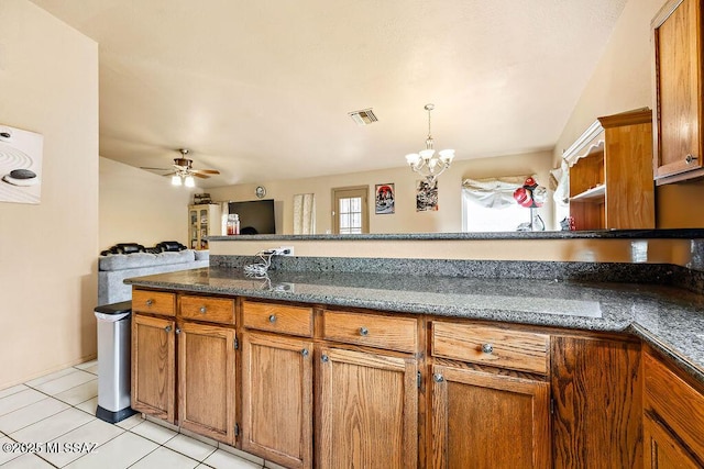 kitchen featuring light tile patterned flooring, pendant lighting, ceiling fan with notable chandelier, and dark stone countertops