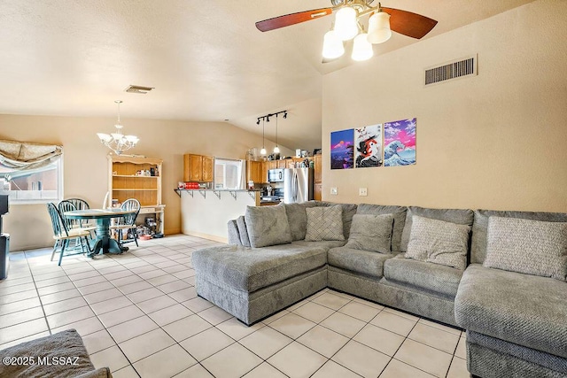 tiled living room featuring ceiling fan with notable chandelier, track lighting, and vaulted ceiling