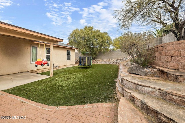 view of yard with a trampoline and a patio area