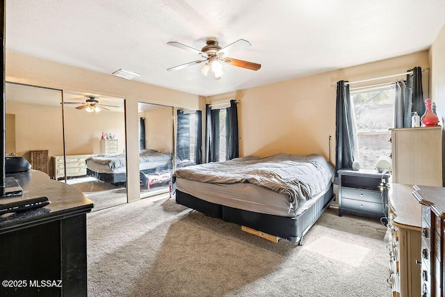 carpeted bedroom with two closets and ceiling fan