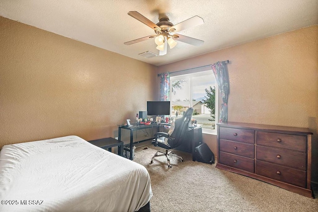 carpeted bedroom featuring ceiling fan and a textured ceiling