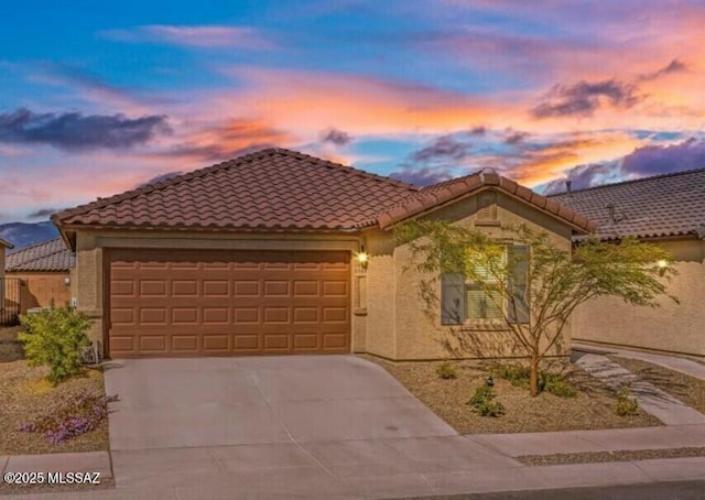 view of front of home with a garage, a tiled roof, driveway, and stucco siding