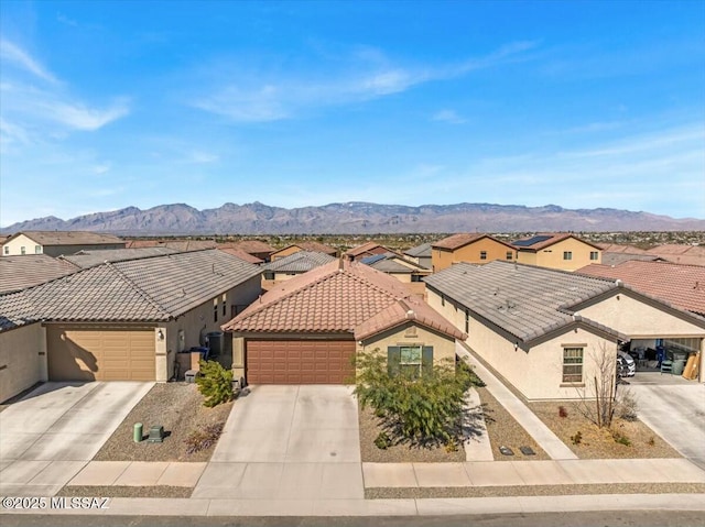 view of front of property featuring a residential view, a garage, a mountain view, concrete driveway, and stucco siding