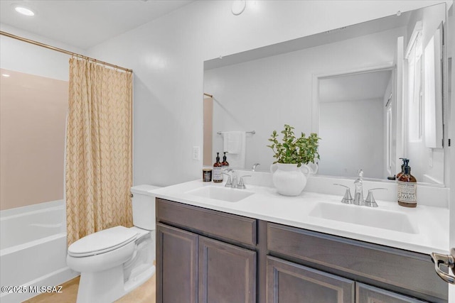 full bathroom with double vanity, a sink, shower / bath combo with shower curtain, and toilet
