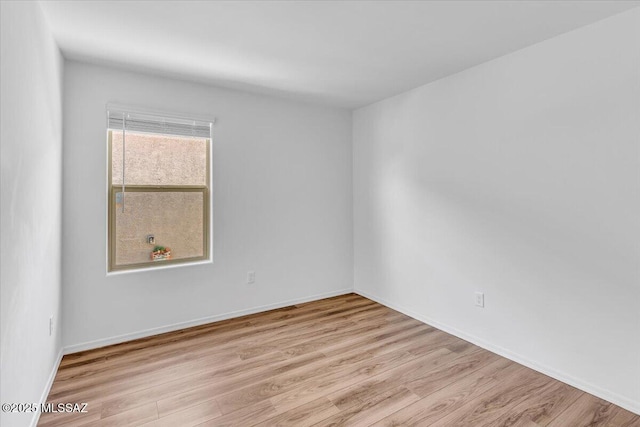 spare room with baseboards and wood finished floors