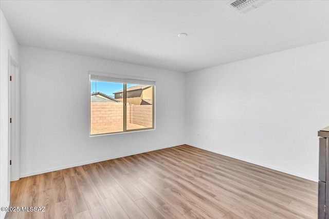 spare room with baseboards, wood finished floors, and visible vents