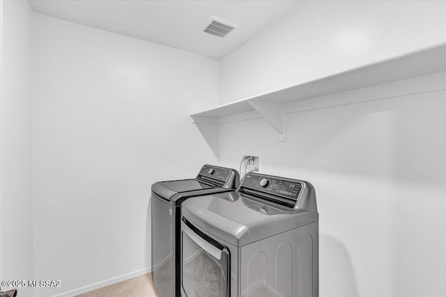 clothes washing area featuring laundry area, baseboards, visible vents, and washing machine and clothes dryer