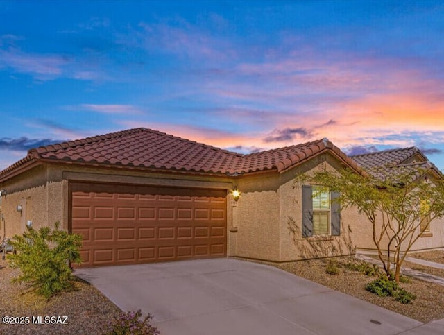 ranch-style house featuring a garage, stucco siding, a tile roof, and concrete driveway