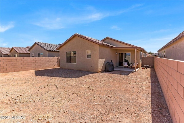 rear view of house with a fenced backyard, a patio area, stucco siding, and a tile roof