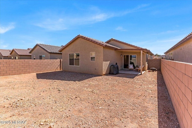 back of house featuring a tiled roof, a patio area, a fenced backyard, and stucco siding