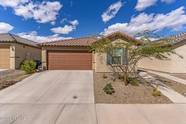view of front of property featuring a tiled roof, a garage, concrete driveway, and stucco siding