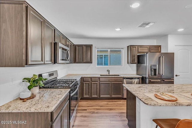 kitchen featuring visible vents, light stone countertops, a sink, stainless steel appliances, and recessed lighting