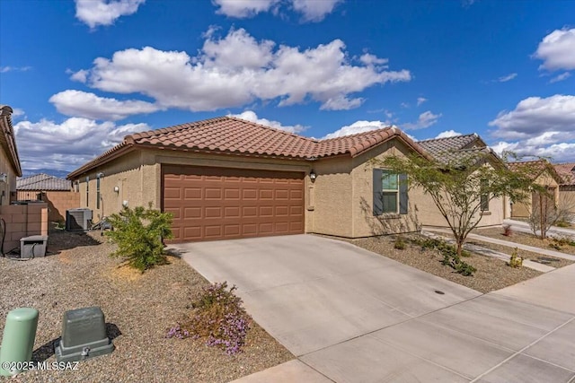 view of front of home featuring central AC unit, concrete driveway, a tile roof, an attached garage, and stucco siding