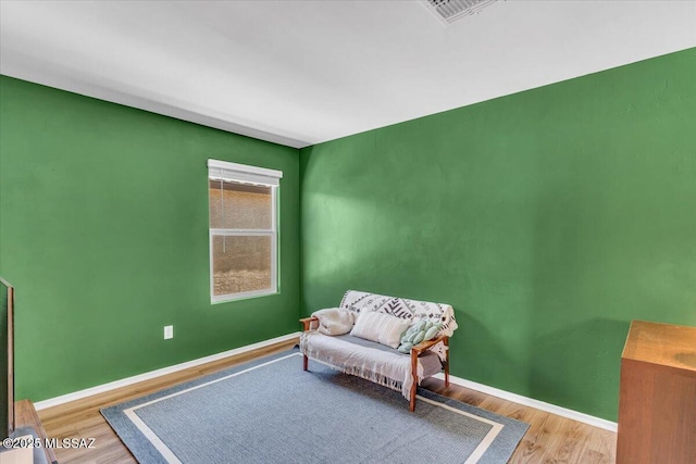 sitting room with baseboards, wood finished floors, and visible vents