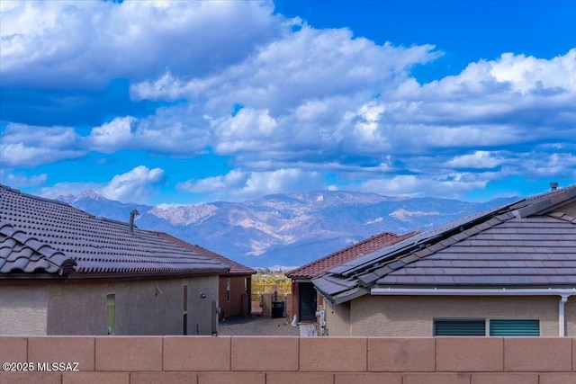 exterior space with a tiled roof, fence, a mountain view, and stucco siding
