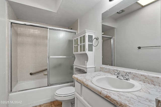 full bathroom featuring vanity, shower / bath combination with glass door, and toilet