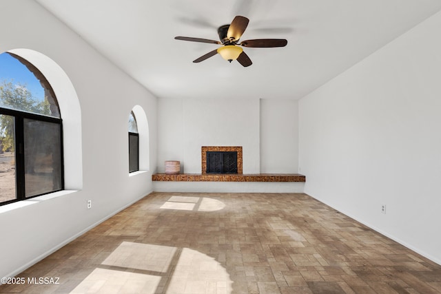 unfurnished living room featuring ceiling fan and plenty of natural light