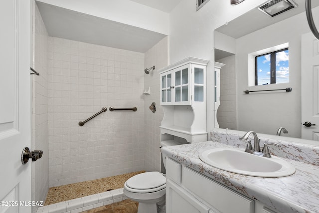 bathroom featuring vanity, toilet, and a tile shower