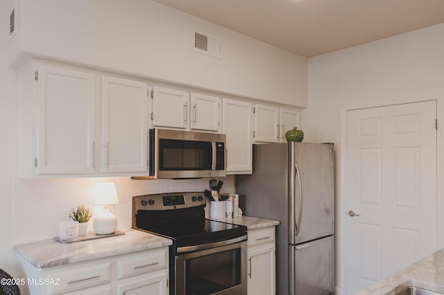 kitchen featuring appliances with stainless steel finishes, white cabinets, and backsplash