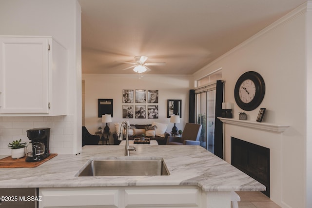 kitchen featuring white cabinetry, sink, crown molding, and light stone countertops