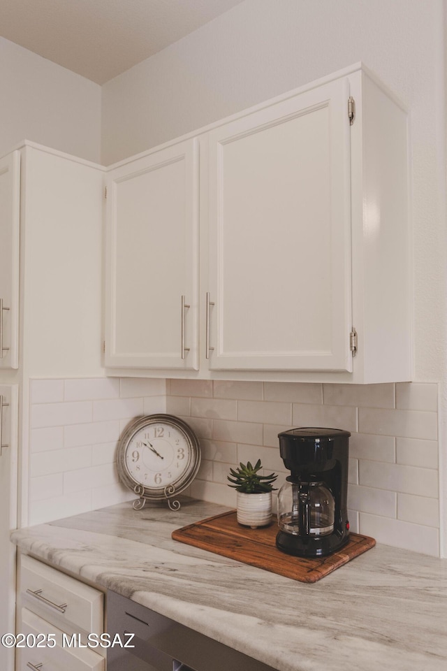 details featuring white cabinetry, light stone countertops, and backsplash