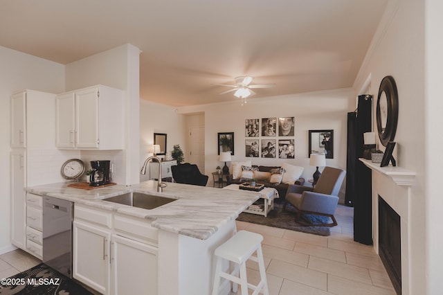 kitchen featuring a kitchen bar, dishwasher, sink, and white cabinets