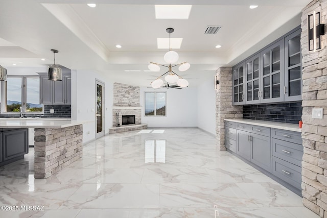 kitchen featuring decorative light fixtures, gray cabinets, and a raised ceiling