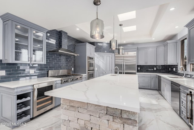 kitchen with hanging light fixtures, an island with sink, appliances with stainless steel finishes, and beverage cooler