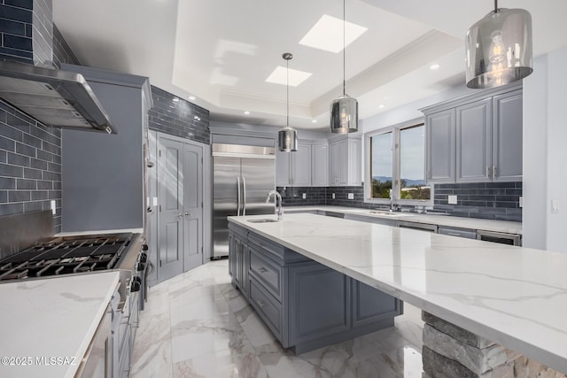 kitchen featuring gray cabinetry, a skylight, light stone countertops, decorative light fixtures, and a raised ceiling