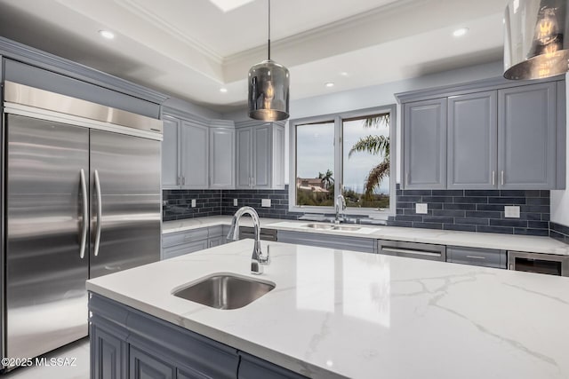 kitchen with appliances with stainless steel finishes, decorative light fixtures, light stone countertops, and sink