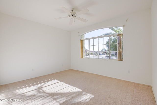 empty room with ceiling fan and light carpet