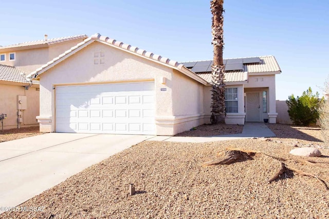 mediterranean / spanish-style home featuring solar panels, an attached garage, and stucco siding