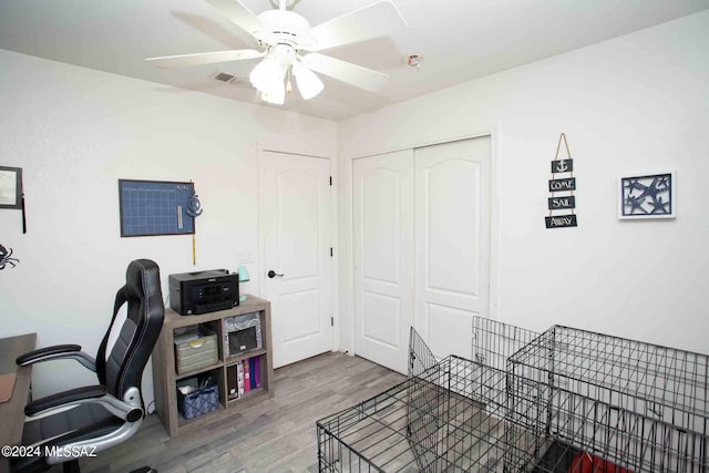 home office with a ceiling fan, visible vents, and wood finished floors