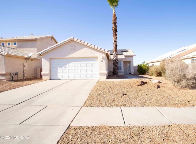 view of front of home with a garage, concrete driveway, a tiled roof, roof mounted solar panels, and stucco siding