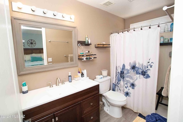 bathroom featuring toilet, wood finished floors, vanity, visible vents, and a shower with curtain