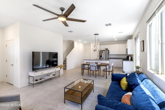 living area with a healthy amount of sunlight, stairs, and visible vents