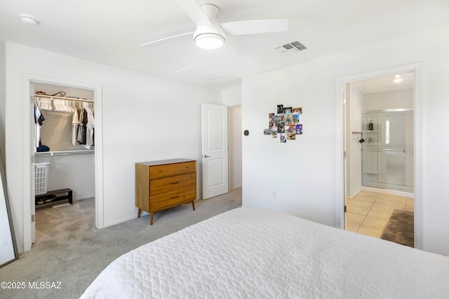 bedroom with ensuite bathroom, light colored carpet, visible vents, a closet, and a walk in closet