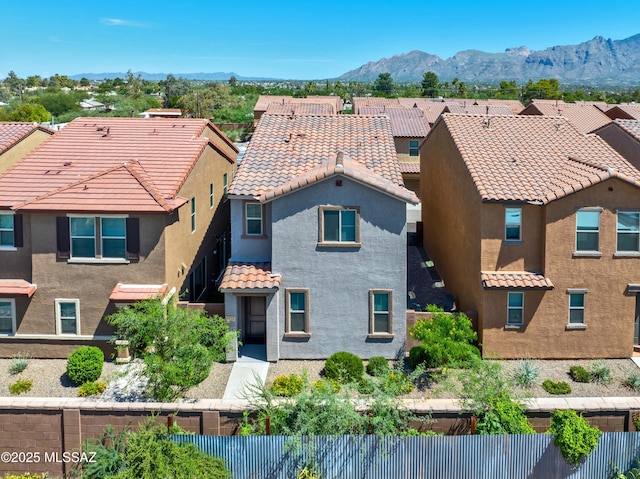 view of front facade with a tile roof, a residential view, fence, a mountain view, and stucco siding