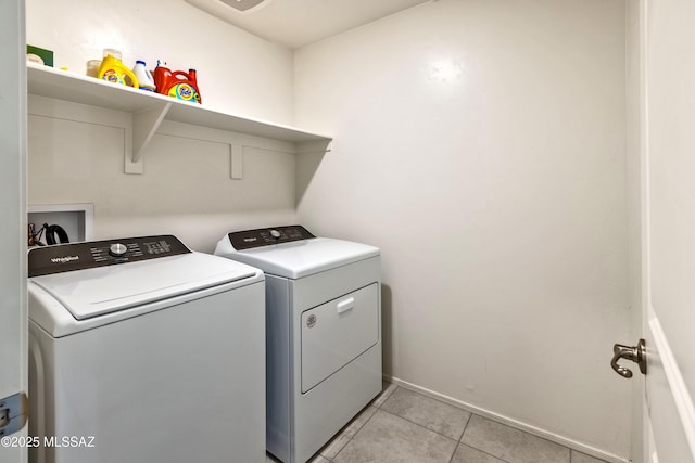 clothes washing area featuring light tile patterned floors, laundry area, independent washer and dryer, and baseboards